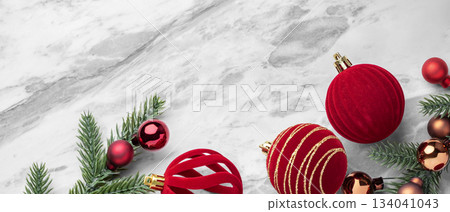 Red velvet baubles, Christmas ball decor and pine branches on marble table background, top view Red velvet baubles, Christmas ball decor and pine branches on marble table background, top view 134041043