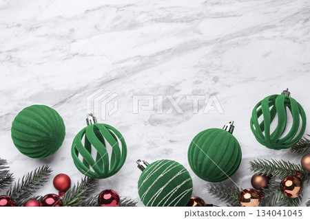 Green Christmas ball ornaments, velvet baubles and pine branches on marble table background, top view Green Christmas ball ornaments, velvet baubles and pine branches on marble table background, top view 134041045