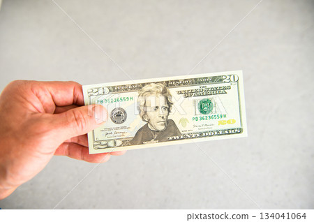 An angle shot of a US $20 bill being held in the left hand and presented from the left side An angle shot of a US $20 bill being held in the left hand and presented from the left side 134041064