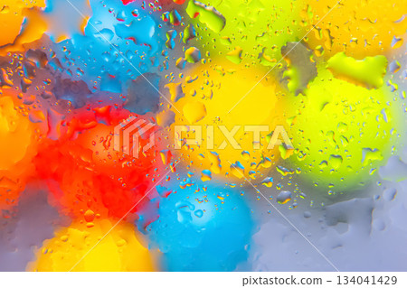Colorful water droplets in red, yellow, blue, and green tones on a shiny surfac 134041429