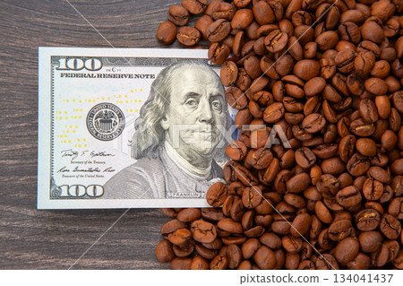 roasted coffee beans surrounding a U.S. $100 bill with Benjamin Franklin' 134041437