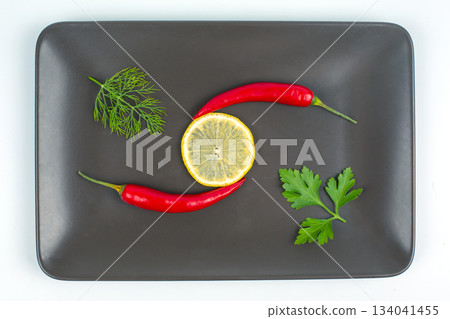 Red hot pepper with lemon on a gray plate. Healthy vegetable food and vitamins Red hot pepper with lemon on a gray plate. Healthy vegetable food and vitamins 134041455