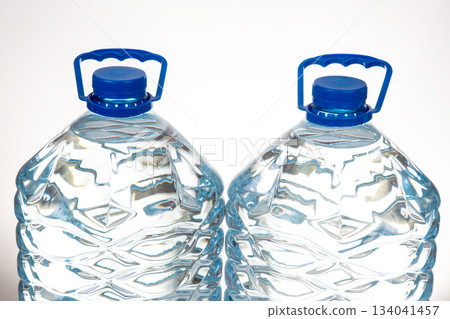 Two plastic water bottles with blue lids and a unique wavy design 134041457