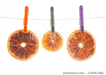 dried pieces of different citrus fruits hang on colored clothespins dried pieces of different citrus fruits hang on colored clothespins 134041466