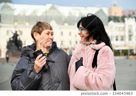 Two Russian friends, 50 and 60 years old, laughing together and looking at each other with affection, showing warmth, trust, mindfulness, and genuine connection. 134043963
