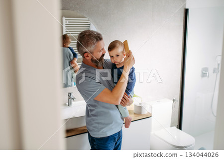 Morning routine in bathroom, father combing son hair. Morning routine in bathroom, father combing son hair. 134044026