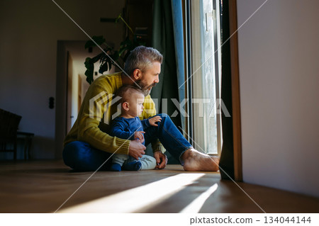 Father with little toddler son looking out of window. 134044144