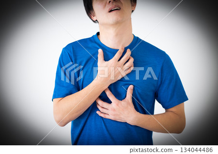 Middle-aged man wearing a T-shirt suffering from chest pain 134044486