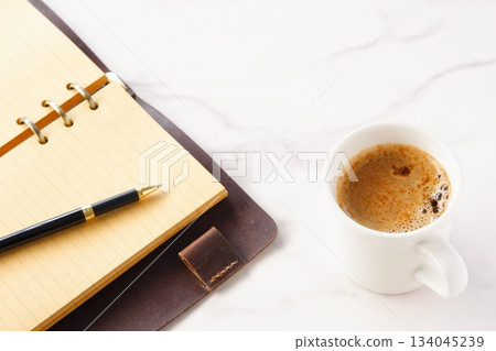 Image of a man working at his desk with a system organizer while drinking a cafe latte, a coffee with plenty of milk 134045239