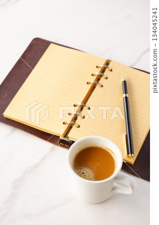 Image of a man working at his desk with a system organizer while drinking a cafe latte, a coffee with plenty of milk Image of a man working at his desk with a system organizer while drinking a cafe latte, a coffee with plenty of milk 134045241