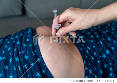 child receiving a medical injection at home during evening hours 134045904