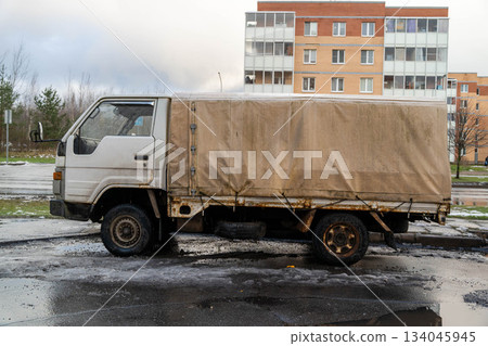 Old delivery truck parked near apartment buildings in urban area during cloudy weather Old delivery truck parked near apartment buildings in urban area during cloudy weather 134045945