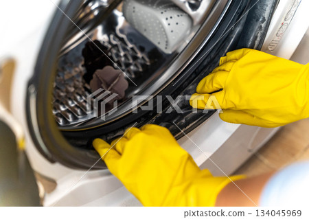 Person cleaning the door seal of a washing machine in a laundry room Person cleaning the door seal of a washing machine in a laundry room 134045969
