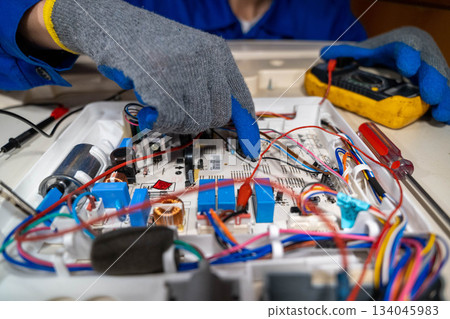 Technician repairs electronic circuit board in workshop during daylight hours Technician repairs electronic circuit board in workshop during daylight hours 134045983