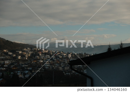 Eastern European Village Nestled Below Snowcapped Peaks 134046160