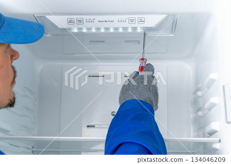 Repair worker fixes inside of refrigerator at home during day 134046209
