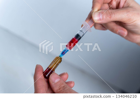 Laboratory technician prepares a vaccination syringe with liquid in a lab setting Laboratory technician prepares a vaccination syringe with liquid in a lab setting 134046210