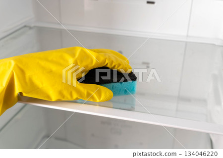 Cleaning a refrigerator shelf with a sponge in a kitchen during the day 134046220