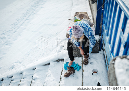 Senior woman getting dressed after swimming in an icy lake for health benefits. Senior woman getting dressed after swimming in an icy lake for health benefits. 134046343