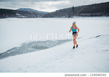 Elderly winter swimmer warming up before cold plunge in lake. Elderly winter swimmer warming up before cold plunge in lake. 134046345