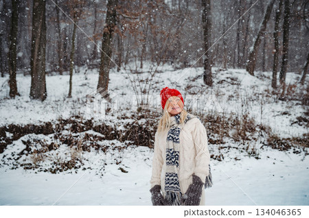 Senior woman enjoying snowfall in winter landscape. 134046365