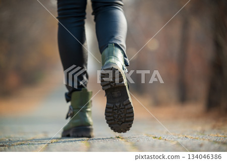 A woman wearing green boots is walking on a path A woman wearing green boots is walking on a path 134046386