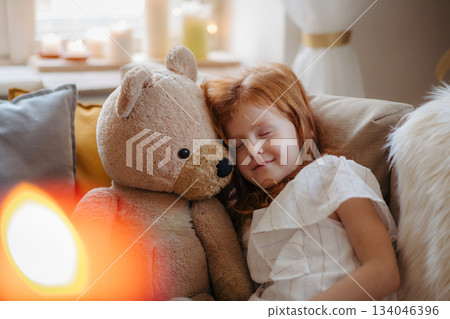 Small girl hugging teddy bear. Christmas mood at home. 134046396