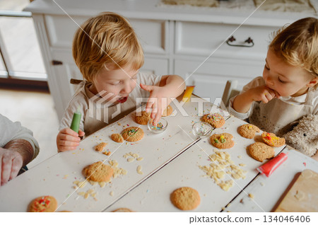 Happy children decorating Christmas cookies at home. Happy children decorating Christmas cookies at home. 134046406