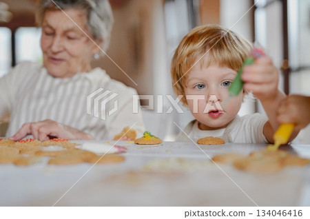 Christmas baking and decorating of cookies with grandma and little kid. Christmas baking and decorating of cookies with grandma and little kid. 134046416