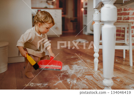 Little girl cleaning up flour mess in kitchen. Little girl cleaning up flour mess in kitchen. 134046419