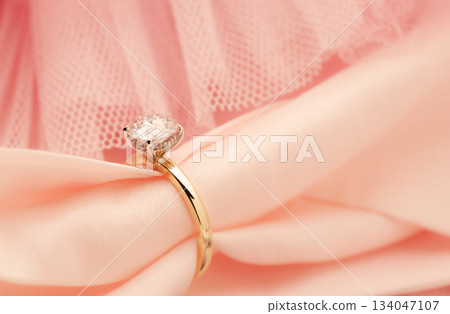 A gold and diamond ring is on a pink cloth 134047107
