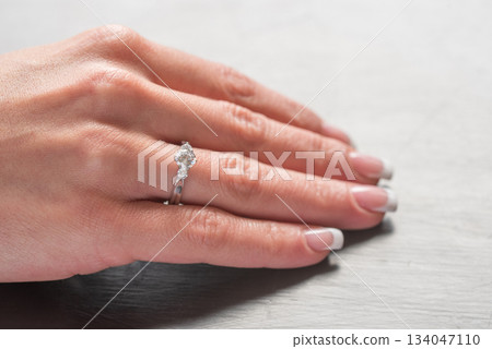 A woman's hand holding a ring with a diamond in the center A woman's hand holding a ring with a diamond in the center 134047110