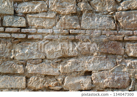 A wall made of stone with a few bricks missing 134047300