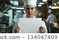 Caucasian female chef angry and holding up a white piece of paper 134047409