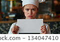 Caucasian female chef angry and holding up a white piece of paper 134047410