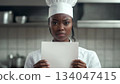 An angry black female chef holding up a white piece of paper 134047415