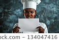 An angry black female chef holding up a white piece of paper 134047416