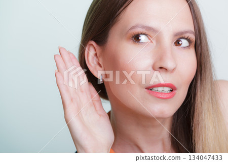 Gossip girl eavesdropping with hand to ear. 134047433