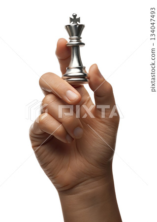 Hand holding reflective silver chess king piece against transparent background, symbolizing strategy, intellect, decisive power 134047493