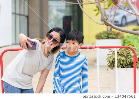 Mother child summer city family woman people street parent son enjoy bright urban outdoor selfie activity smiling with happiness capturing memorable moment together on bustling street background. 134047561