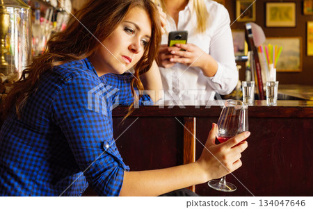 Sad girl with alcohol glass in pub club 134047646