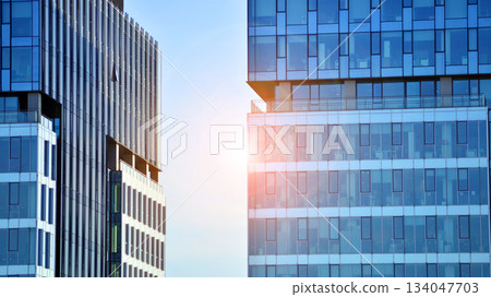 Structural glass wall reflecting blue sky. Abstract modern architecture fragment. Glass building with transparent facade of the building and blue sky. Contemporary architectural background. Structural glass wall reflecting blue sky. Abstract modern architecture fragment. Glass building with transparent facade of the building and blue sky. Contemporary architectural background. 134047703