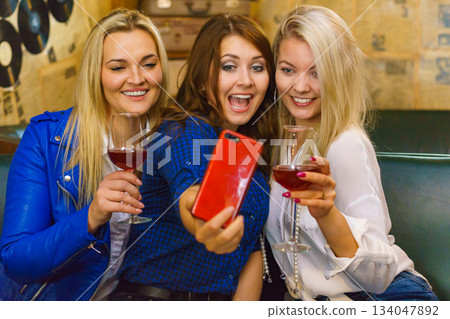 Girls in pub club taking self photo with phone Girls in pub club taking self photo with phone 134047892