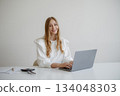 Professional woman working on laptop at a minimalistic desk in a bright, modern office during the day 134048303