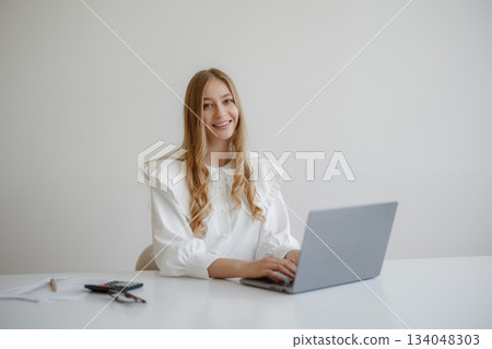 Professional woman working on laptop at a minimalistic desk in a bright, modern office during the day Professional woman working on laptop at a minimalistic desk in a bright, modern office during the day 134048303