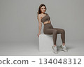 Model poses confidently in stylish activewear against a neutral background, showcasing fitness fashion and modern design 134048312