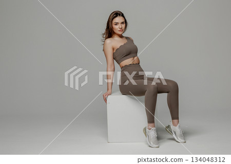 Model poses confidently in stylish activewear against a neutral background, showcasing fitness fashion and modern design 134048312