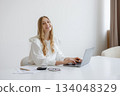 Young woman working on laptop in bright modern workspace during daytime 134048329