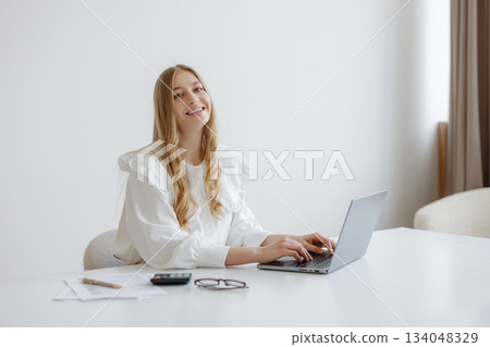 Young woman working on laptop in bright modern workspace during daytime 134048329