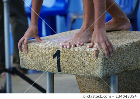Athlete on the starting block of the swimming pool, competition Athlete on the starting block of the swimming pool, competition 134048354